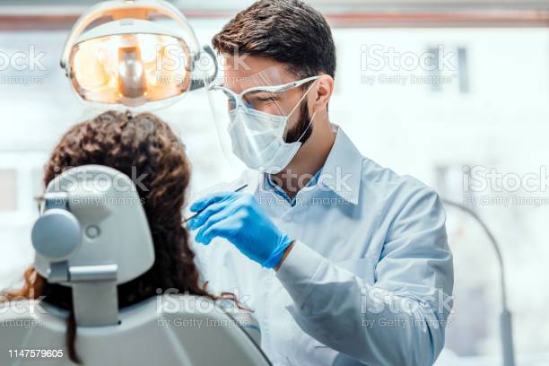Dentist working in dental clinic with patient in the chair. | Studio Smiles Cheap Invisalign